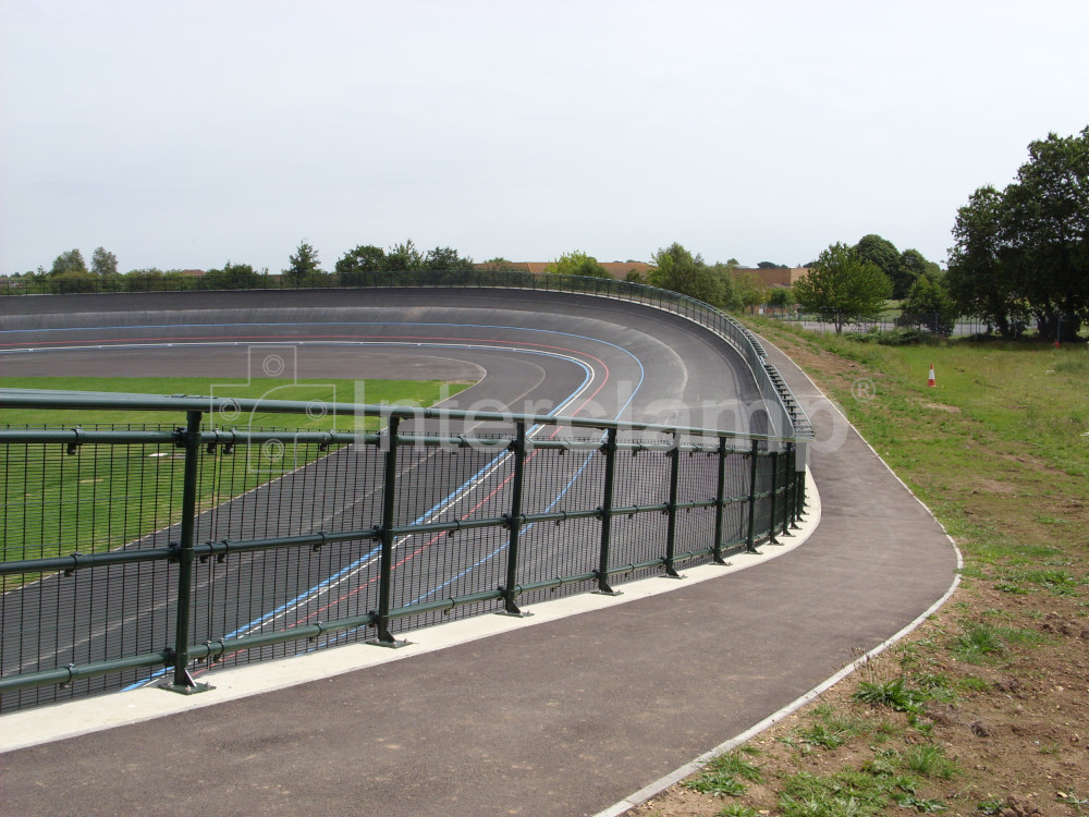 Close-up of dark green Interclamp key clamp DDA fittings forming a safety barrier at a velodrome, showcasing the secure and professional finish